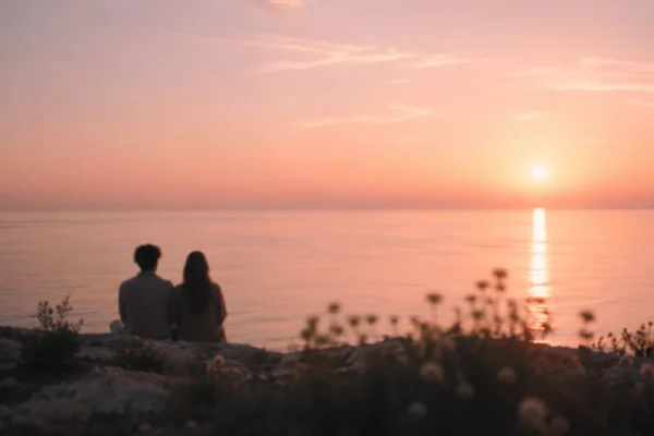 Flamme jumelle : deux silhouettes assises face au coucher de soleil au bord de l'eau